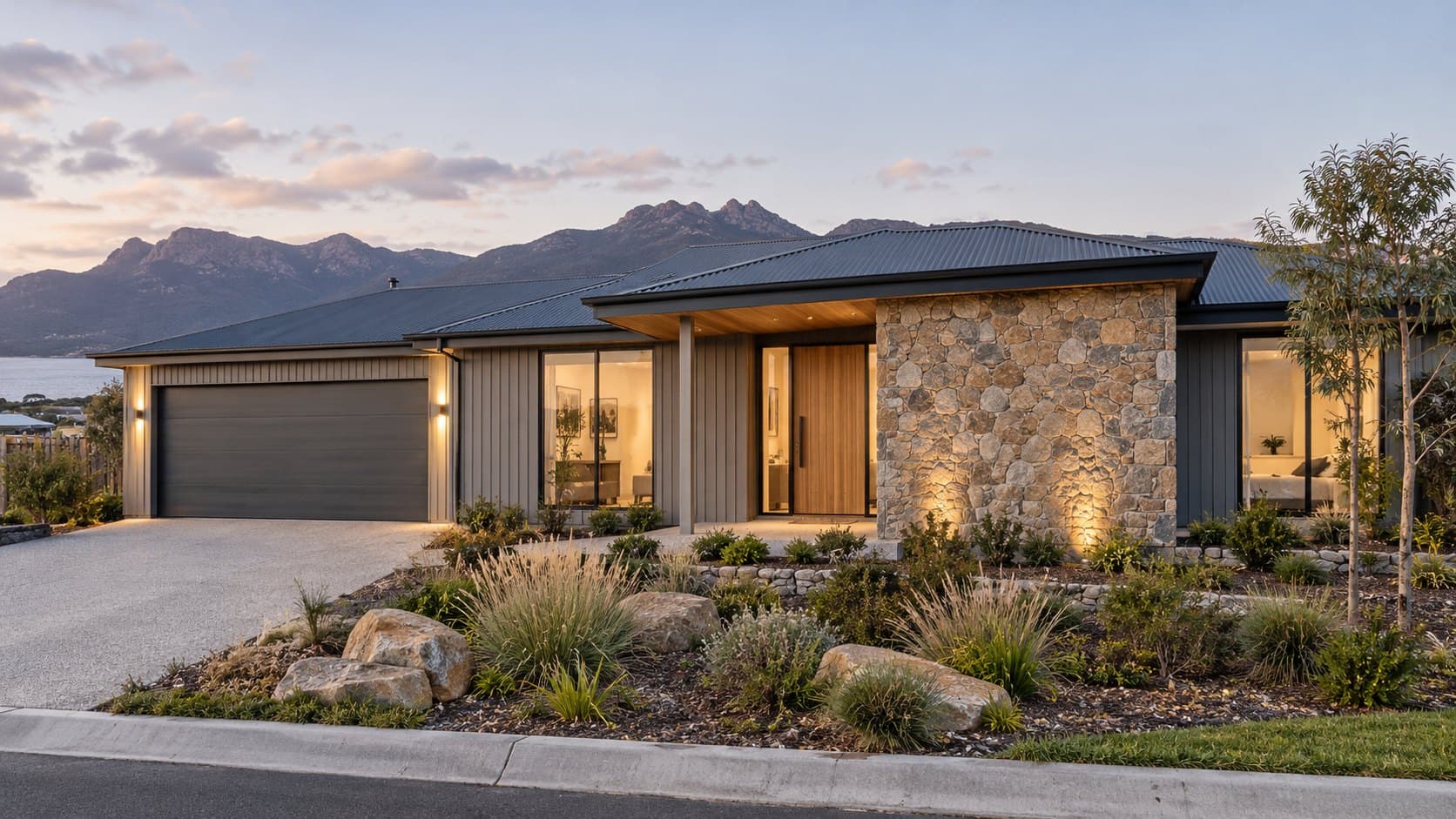 The Freycinet, a single-storey home with a stone feature wall and timber door, with mountains behind